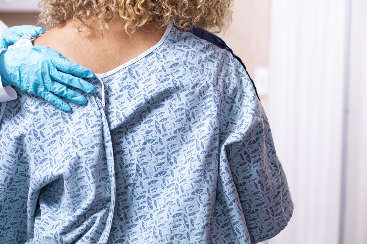 Young African American woman prepares for a breast exam, mammogram from her gynecologist doctor at hospital or clinic. Women's health issues. Breast Cancer awareness.